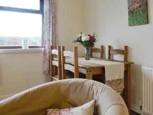 a dining room table and chairs with a vase of flowers at Beuchan Bungalow in Closeburn