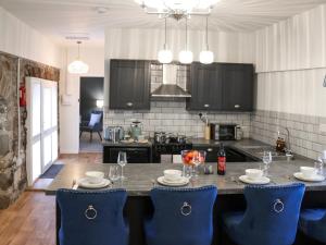 a kitchen with a table with blue chairs in it at Stable End in Llandysul