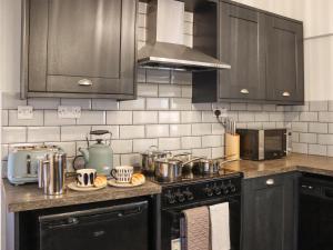 a kitchen with black cabinets and a stove with pots and pans at Stable End in Llandysul