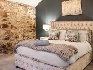 a bedroom with a large bed with a stone wall at Stable End in Llandysul