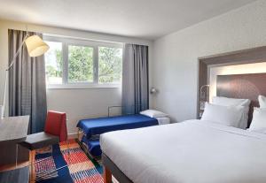 a hotel room with a bed and a desk and window at B&B HOTEL Cergy Port 4 étoiles in Cergy +35 photos