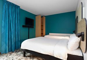 a bedroom with two beds and a blue wall at B&B HOTEL Rouen Centre Rive Gauche in Rouen