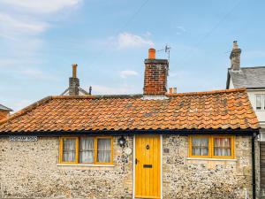 a stone house with a yellow door and two chimneys at Corner Cottage in Saxmundham