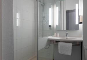 a white bathroom with a shower and a sink at B&B HOTEL Amiens Centre Cathédrale in Amiens +40 photos