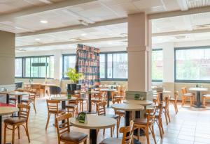 a dining room with tables and chairs and windows at B&B HOTEL Amiens Centre Cathédrale in Amiens