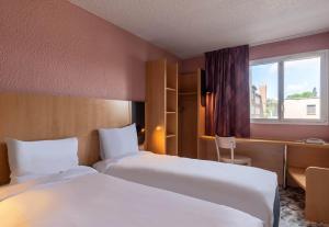 a hotel room with two beds and a window at B&B HOTEL Amiens Centre Cathédrale in Amiens