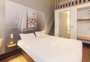 a bedroom with a large white bed and a staircase at B&B HOTEL Bayonne in Bayonne