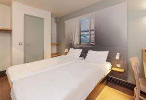a large white bed in a room with a window at B&B HOTEL Bayonne in Bayonne
