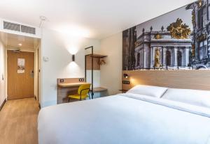 a hotel room with a white bed and a desk at B&B HOTEL Lille Roubaix Centre Grand-Place in Roubaix