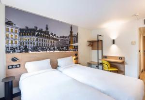 a bedroom with two beds and a picture of a city at B&B HOTEL Lille Roubaix Centre Grand-Place in Roubaix