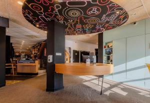 a large ceiling in a lobby with a wooden table at B&B HOTEL Lille Roubaix Centre Grand-Place in Roubaix +37 photos