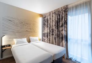 two beds in a hotel room with a window at B&B HOTEL Lille Villeneuve d'Ascq Grand Stade 3 étoiles in Villeneuve d'Ascq +30 photos