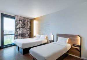 a hotel room with two beds and a window at B&B HOTEL Lille Villeneuve d'Ascq Grand Stade 3 étoiles in Villeneuve d'Ascq