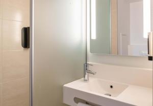 a bathroom with a white sink and a mirror at B&B HOTEL Lyon Eurexpo Chassieu in Chassieu
