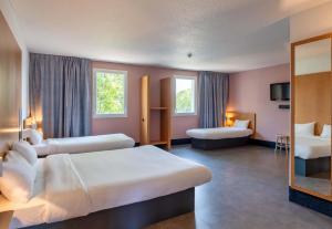 a hotel room with two beds and a mirror at B&B HOTEL Lyon Eurexpo Chassieu in Chassieu