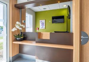 a office with a green wall with a tv on it at B&B HOTEL Lyon Eurexpo Chassieu in Chassieu