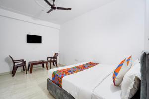a bedroom with a bed and chairs and a ceiling fan at FabHotel HR Residency in New Delhi