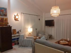 a living room with a couch and chairs and a tv at ELENI'S HOUSE FOR VACATION in Nea Plagia