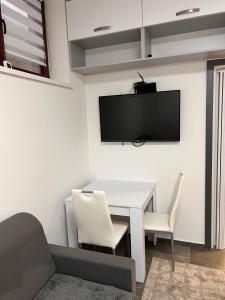 a living room with a white table and a tv on a wall at Centrum Apartman LEYLA 8 in Bardejov