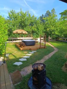 a backyard with a grill and a table and an umbrella at Ptit Ranch "Ô Rêves Atypiques" spa privatif in Boucé