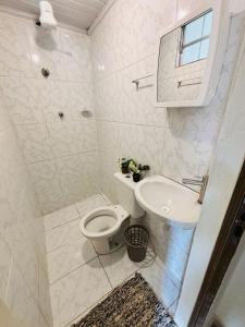 a white bathroom with a toilet and a sink at Pousada e Pensionato Consuelo in Montes Claros