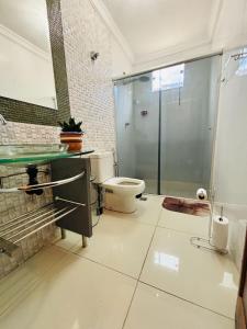 a bathroom with a toilet and a glass shower at Pousada e Pensionato Consuelo in Montes Claros