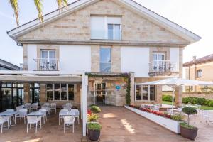 an outdoor patio with tables and chairs and a building at Hotel Silken Don Pepe y Don Pepe Ría in Ribadesella