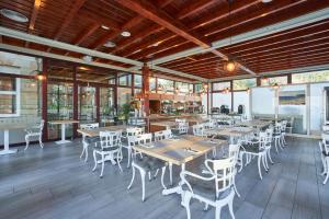 a restaurant with wooden tables and white chairs at Hotel Silken Don Pepe y Don Pepe Ría in Ribadesella