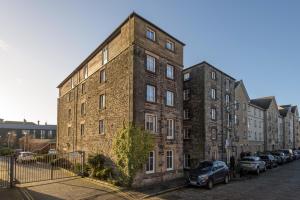 a large brick building with cars parked in front of it at Cozy 3BR escape near Edinburgh centre in Edinburgh