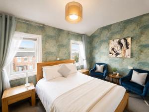 a bedroom with a bed and two blue chairs at The Fossil Tree Hotel in Blackpool +187 photos