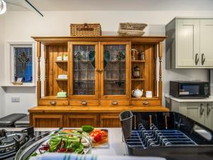 a kitchen with a wooden cabinet with stained glass at Flint Cottage in Saxmundham