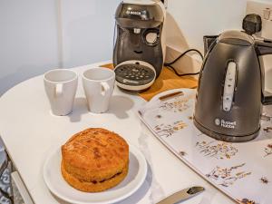 a table with a coffee maker and a plate of cake at Flint Cottage in Saxmundham +9 photos