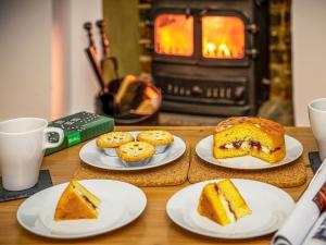 a table with plates of cake and pastries and a fireplace at Flint Cottage in Saxmundham