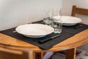 a table with two white plates and glasses on it at Studio 766 – LA TARENTAISE in Brides-les-Bains +12 photos