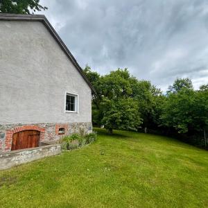 an old stone house with a grassy yard next to a building at Willa Pod Dębem in Koczarki