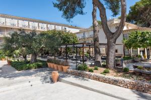 a large building with trees and tables and chairs at Hotel Castell dels Hams in Porto Cristo