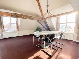 a dining room with a table and chairs and windows at Huize de Lekpoort - The Stork Loft - Loft Apartment in Vianen Center in Vianen