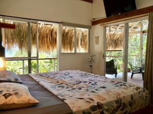 a bedroom with a large bed in front of windows at Santa Lova Eco-hostel Isla Tintipan in Tintipan Island