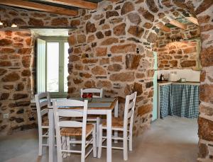 a dining room with a stone wall and a table and chairs at Koumaros Cycladic Suites in Koumáros