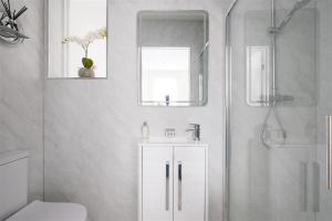 a white bathroom with a shower and a sink at Beeches Retreat in Shrewsbury