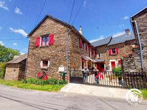 a brick house with red windows on a street at L'Escapade de JOS , chambres et table d'hôte in Pont-de-Salars