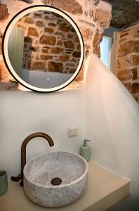a bathroom with a stone sink and a mirror at Koumaros Cycladic Suites in Koumáros