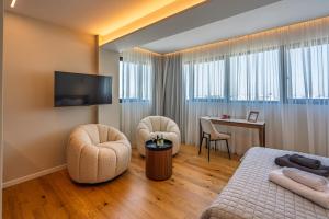 a hotel room with a bed and chairs and a desk at Sky Suites Nicosia in Strovolos