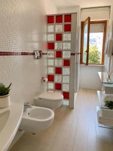 a bathroom with two white toilets and a red wall at La Casa al Mare in Pescara