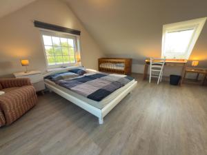a bedroom with a bed and a couch and two windows at Minser Deichhaus in Wangerland