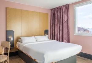 a large white bed in a room with a window at B&B HOTEL Martigues Port-de-Bouc in Port-de-Bouc
