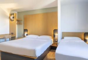 two white beds in a room with a table at B&B HOTEL Martigues Port-de-Bouc in Port-de-Bouc +25 photos