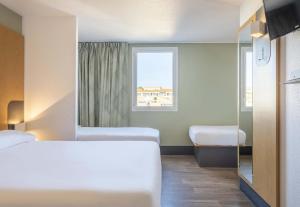 a hotel room with two beds and a window at B&B HOTEL Martigues Port-de-Bouc in Port-de-Bouc
