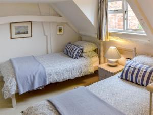 a attic bedroom with two beds and a window at Sea Breeze in Blakeney
