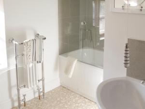 a white bathroom with a tub and a sink at Sea Breeze in Blakeney +6 photos